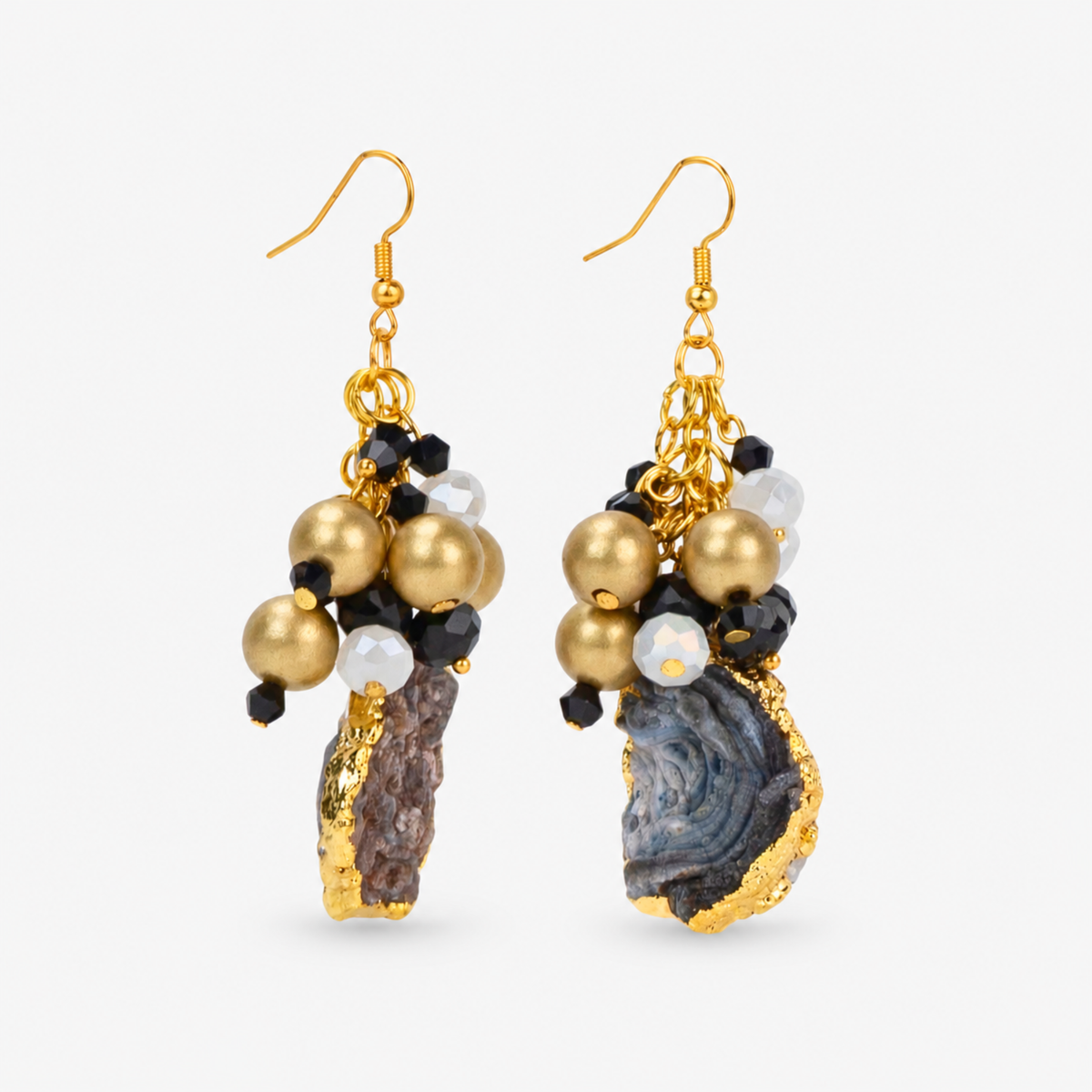 Chrysallis dangle earrings featuring irregular natural agate stones edged in gold with black and white bead accents. Sassy Jones natural agate earrings with textured stone drops, matte gold beads, and faceted black accents.

Black, white, and gold dangle earrings featuring clustered beads above natural raw edge agate slices.

Chrysallis Natural Black/Gold earrings featuring unique agate stone drops suspended beneath dimensional bead clusters.