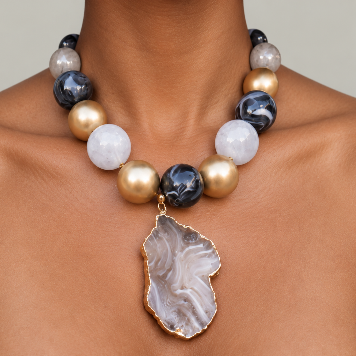 Natural stone statement necklace featuring a gray and black agate slice edged in a Gold tone finish.