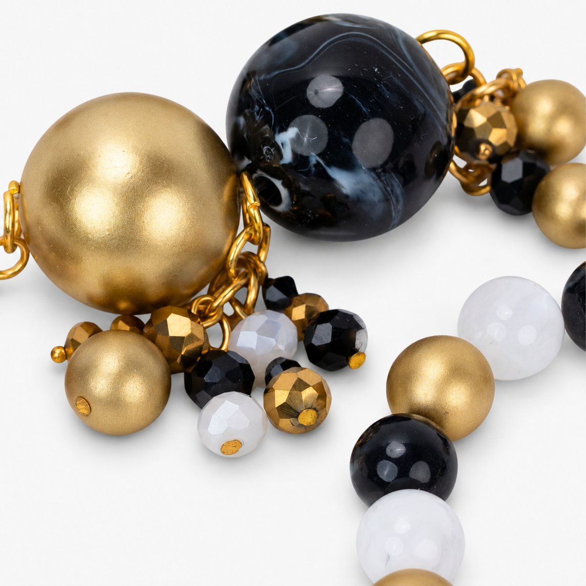Chrysallis Black Gold bracelet with a large raw agate centerpiece, black marbled beads, clear accents, and brushed gold beads.
Natural stone stretch bracelet featuring gray agate slices with Gold tone finish edging and chunky black beads.

Close-up of Chrysallis chunky bracelet featuring organic agate stones, metallic gold beads, and small dangling accents.

Black clear and gold statement bracelet featuring natural agate centerpieces and dimensional clustered bead details.