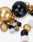 Chrysallis Black Gold bracelet with a large raw agate centerpiece, black marbled beads, clear accents, and brushed gold beads.
Natural stone stretch bracelet featuring gray agate slices with Gold tone finish edging and chunky black beads.

Close-up of Chrysallis chunky bracelet featuring organic agate stones, metallic gold beads, and small dangling accents.

Black clear and gold statement bracelet featuring natural agate centerpieces and dimensional clustered bead details.