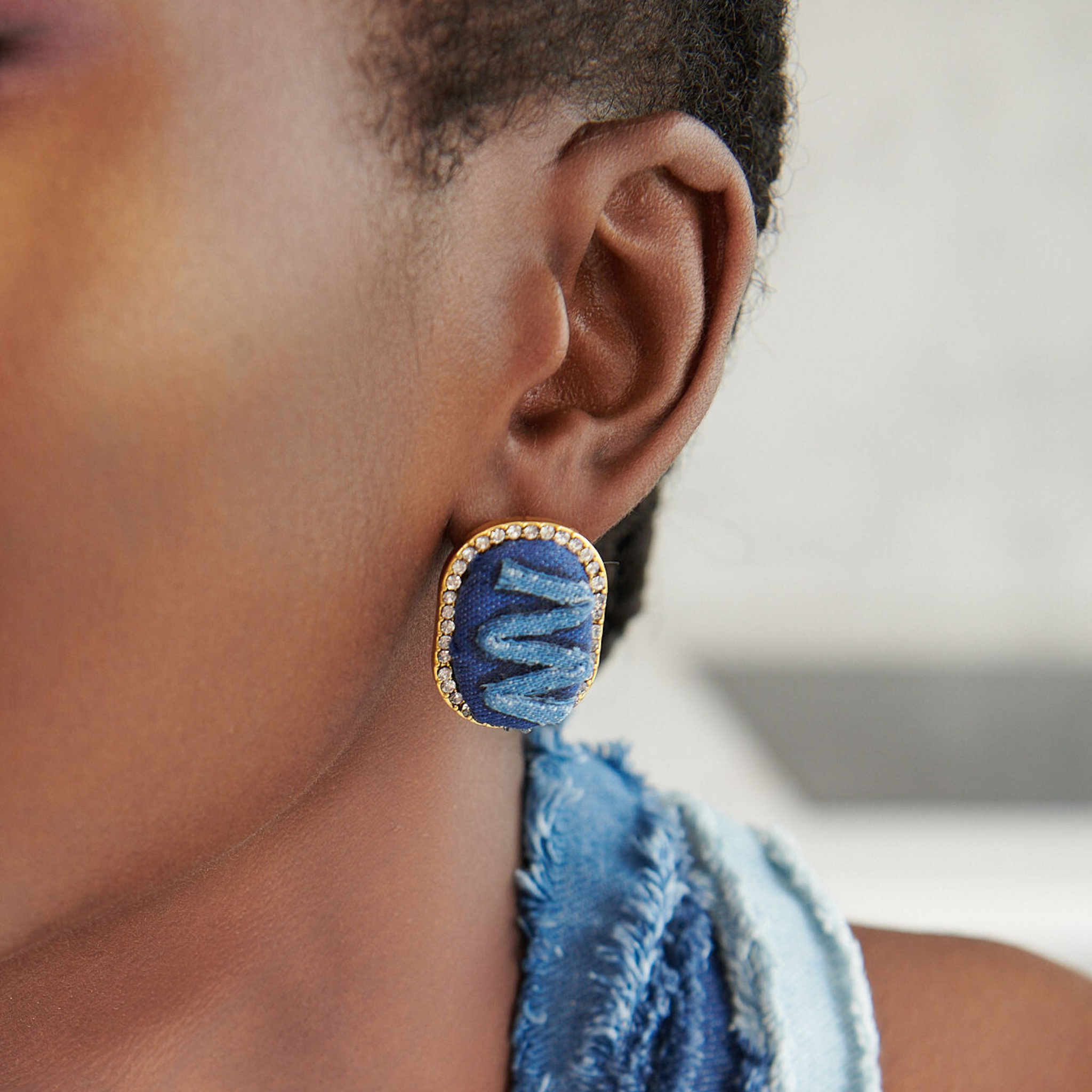 Handcrafted oval earrings made with denim fabric, accented by a light blue design and surrounded by rhinestones