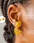 Dina Gold earrings shown on ear with a smaller textured sphere above a larger openwork globe.