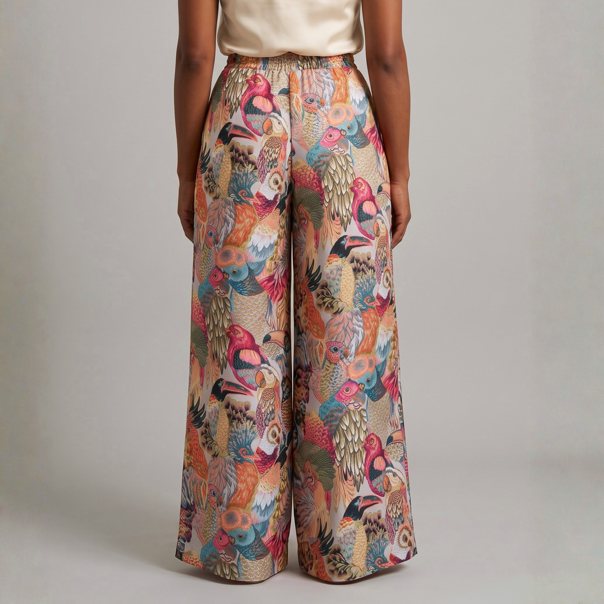 Back view of Fawna wide leg pants showcasing an allover tapestry inspired bird motif in teal, coral, pink, blue and cream.