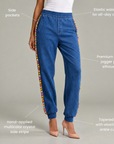 Womens blue denim jogger pants with multicolor jeweled side detailing and elasticized waist.