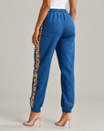 Gemma Crystal Jogger Pant in blue denim featuring colorful crystal embellishments along the outer legs.