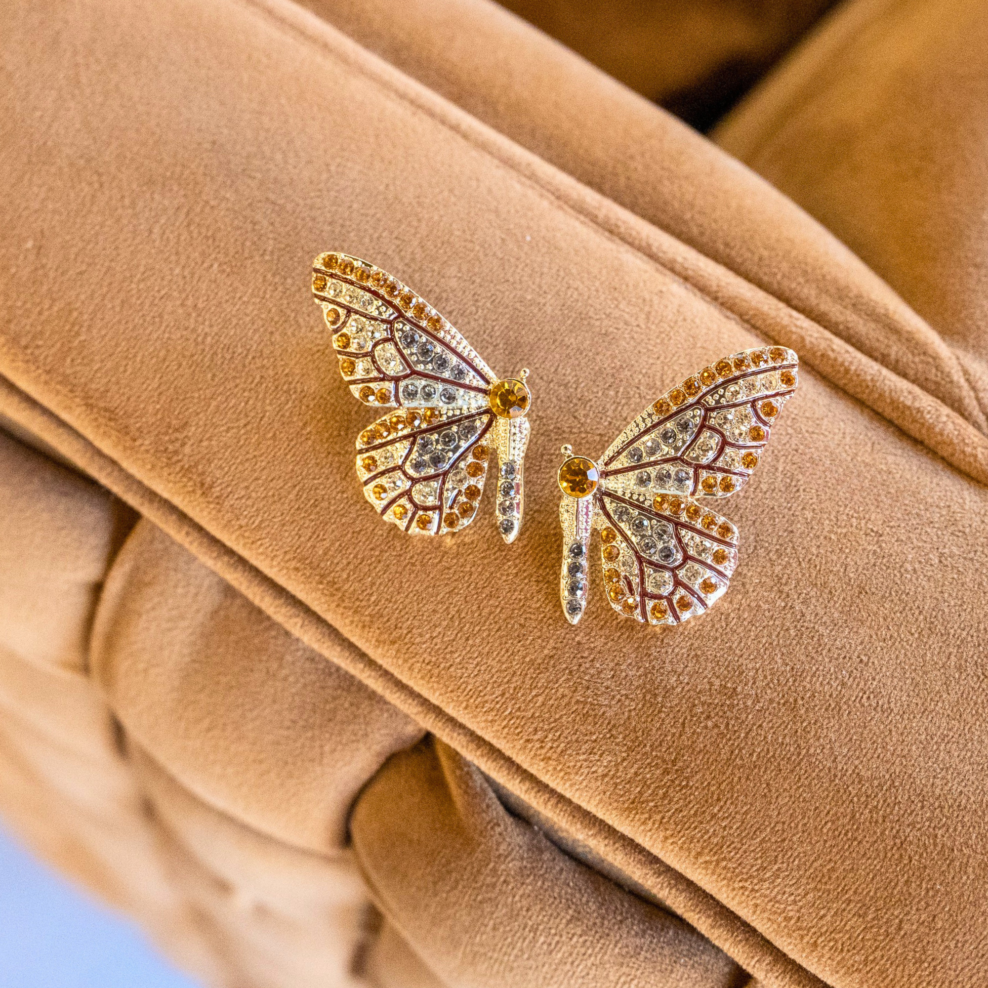 Gold butterfly stud earrings with champagne and smoky crystals in a delicate yet radiant design.