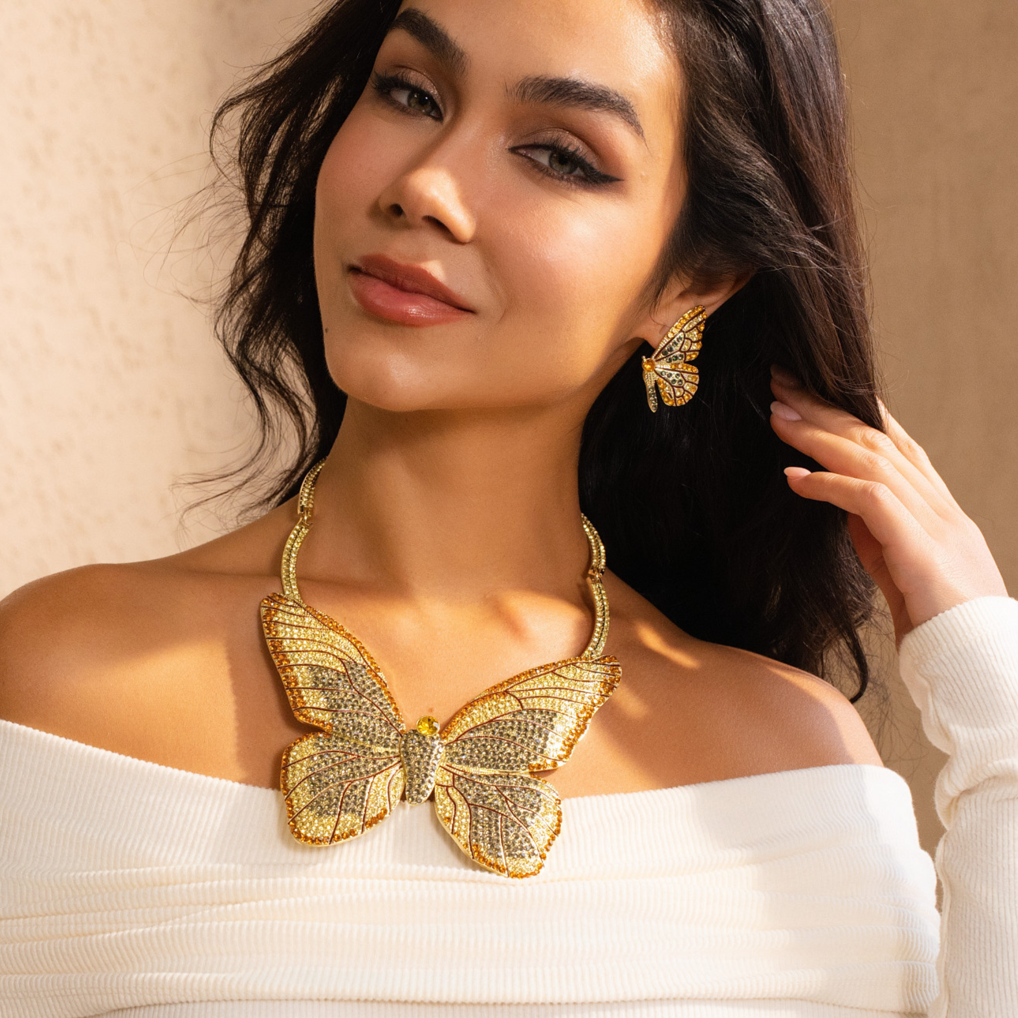 Gold butterfly stud earrings with champagne and smoky crystals in a delicate yet radiant design.