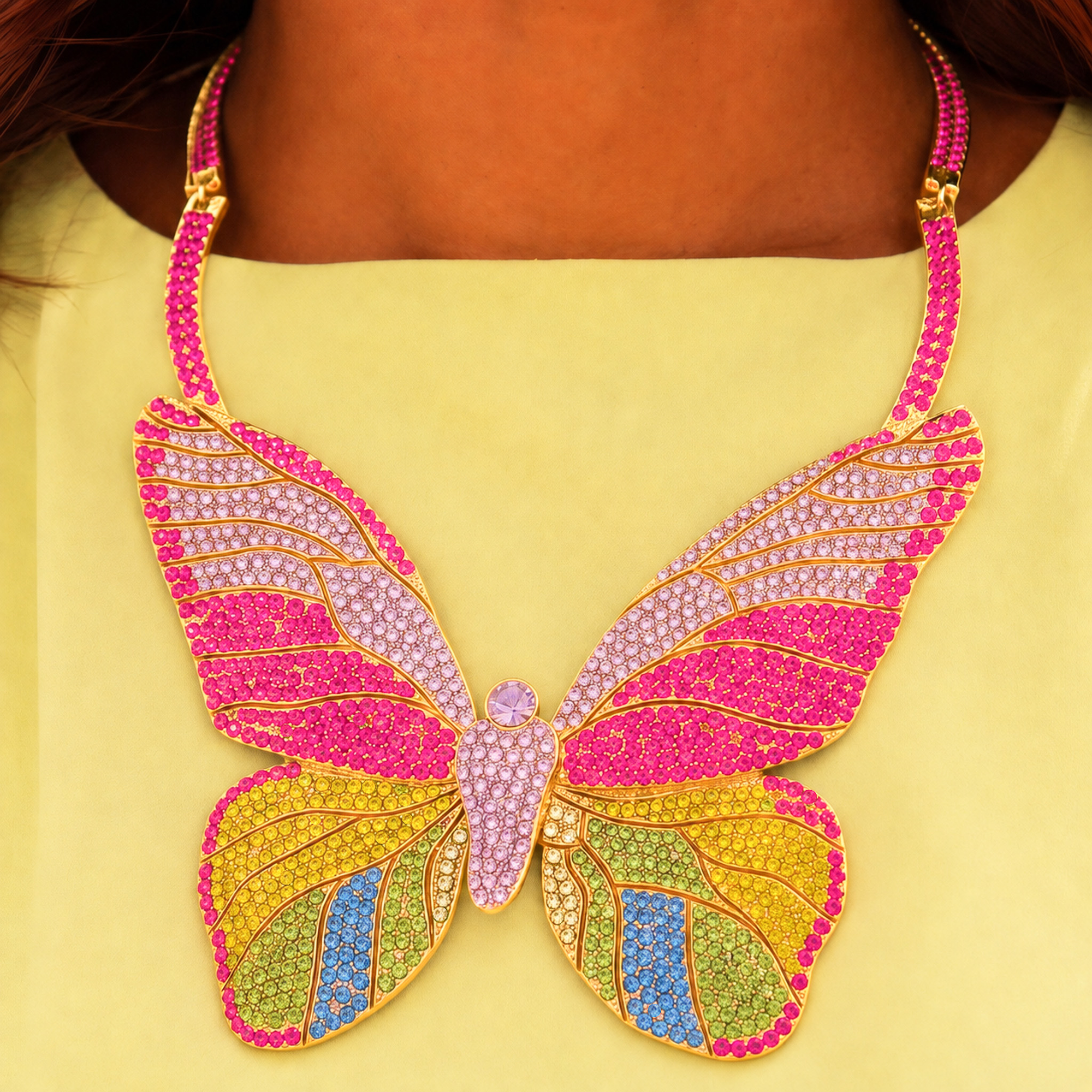 Statement butterfly bib necklace featuring vibrant multicolored crystals in coral, pink, gold, turquoise, and emerald with gold tone detailing.
