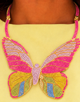 Statement butterfly bib necklace featuring vibrant multicolored crystals in coral, pink, gold, turquoise, and emerald with gold tone detailing.