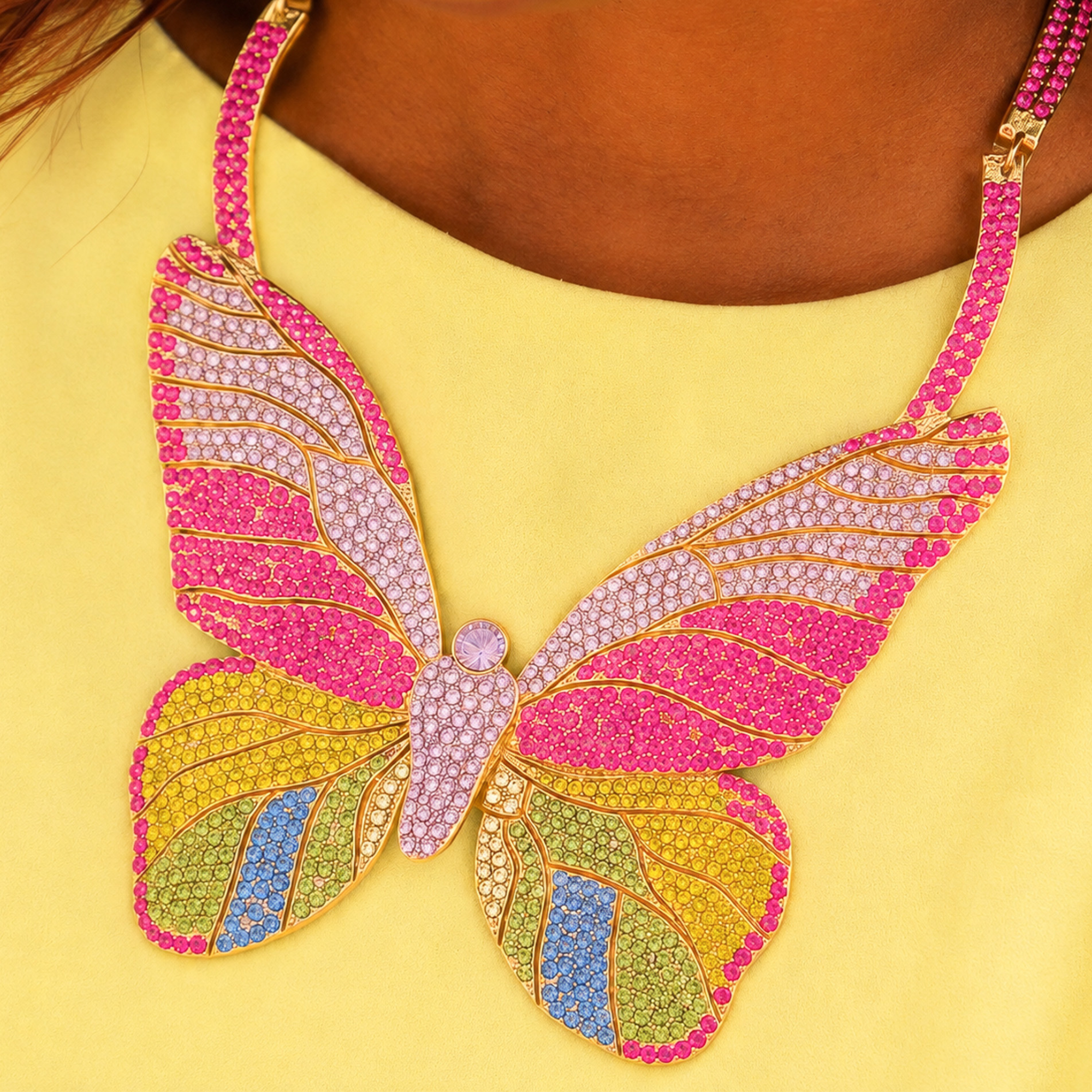 Statement butterfly bib necklace featuring vibrant multicolored crystals in coral, pink, gold, turquoise, and emerald with gold tone detailing.
