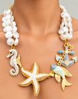 Statement pearl necklace featuring a large pearl detailed starfish, seahorse, colorful fish and enamel anchor charms.