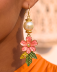 Tropical floral dangle earrings featuring luminous pearl accents, hand painted pink flowers, gold tone detailing, and lightweight drop hooks.