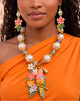 Colorful tropical statement necklace featuring luminous pearls, vibrant floral accents, artisan glass beads, and a detailed pink and gold parrot pendant.