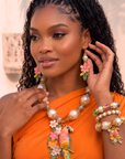 Tropical floral dangle earrings featuring luminous pearl accents, hand painted pink flowers, gold tone detailing, and lightweight drop hooks.