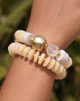 Two-piece ivory stretch bracelet stack featuring coconut-inspired beads, brushed gold accents, frosted white details, and a faceted clear focal bead.