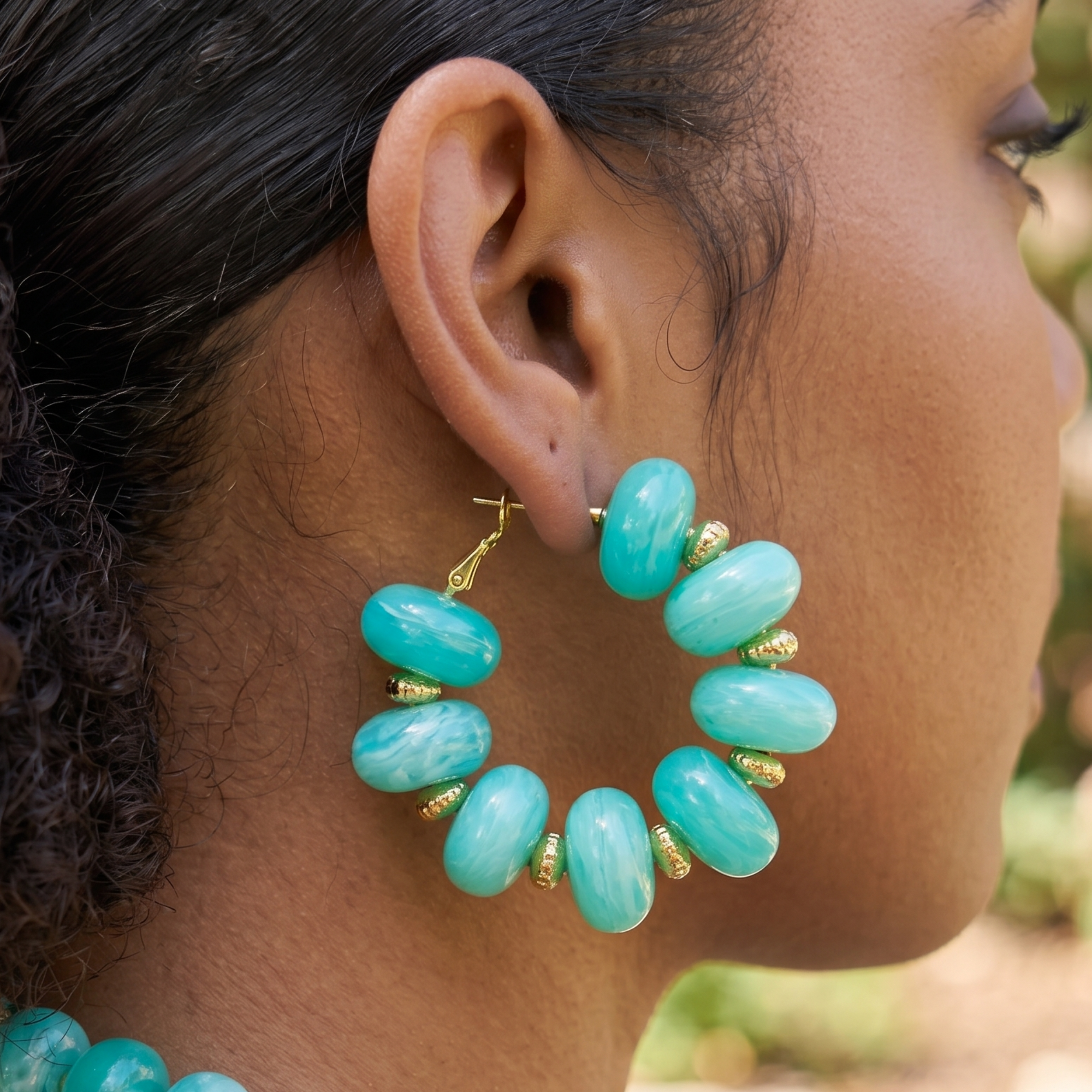 Teal statement hoop earrings featuring oversized marbled turquoise beads and gold-tone accents by Sassy Jones.