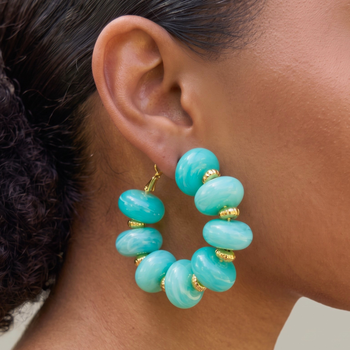 Kamaria Coconut Shell Statement Hoops in Riviera Teal featuring oversized marbled teal coconut shell pieces and gold accents.