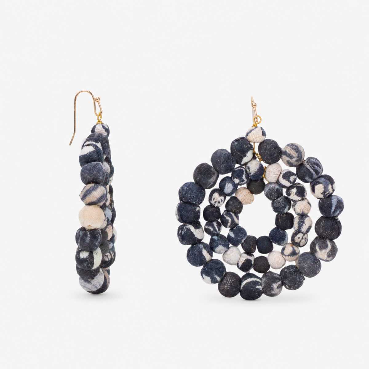 1. Close view of oversized black and white cloth bead dangle earrings with layered circular construction.