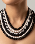 Multistrand black and white bib necklace featuring rounded cloth beads and adjustable fabric ties.