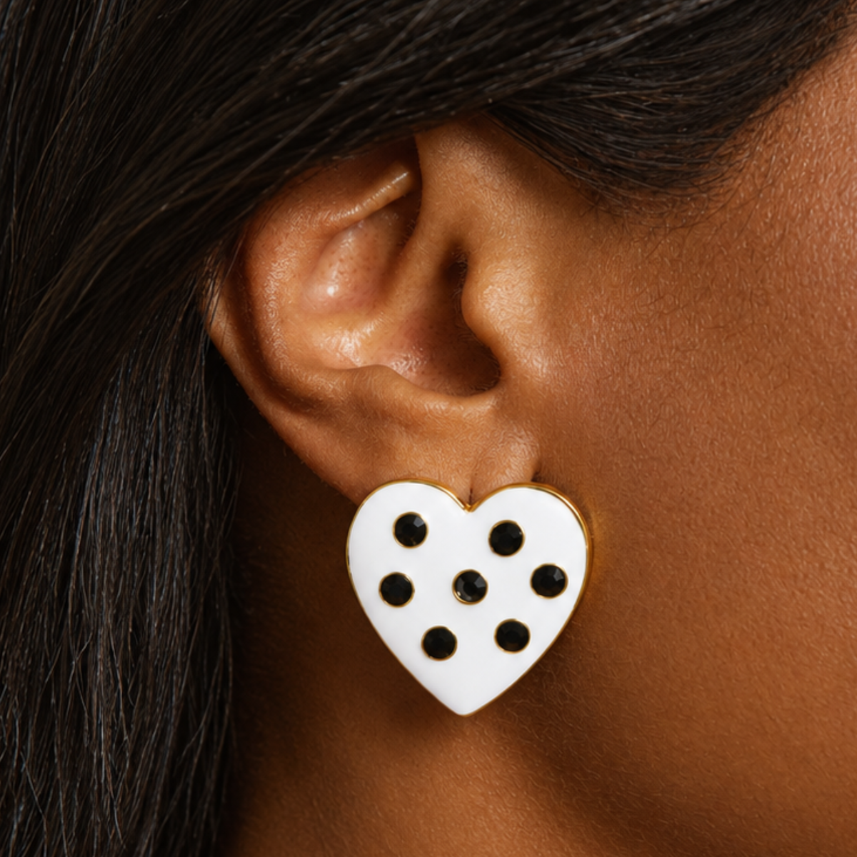 Pair of black and white heart shaped stud earrings with glossy enamel inspired surfaces and dark crystal accents.