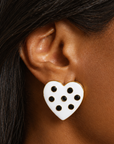 Pair of black and white heart shaped stud earrings with glossy enamel inspired surfaces and dark crystal accents.