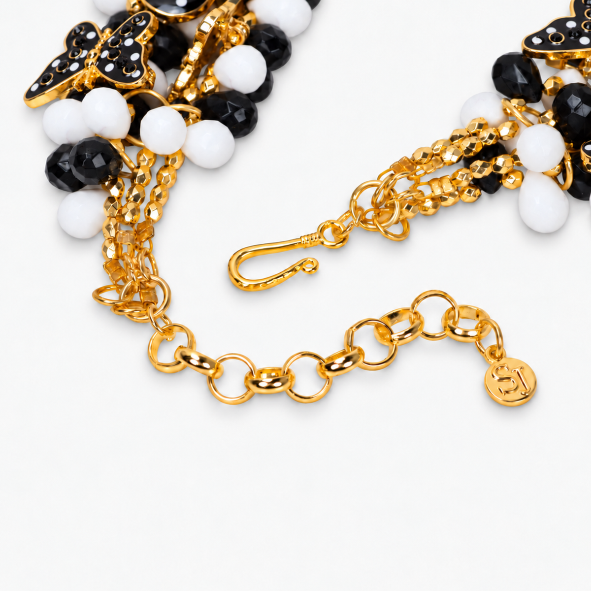 Black and white beaded bib necklace with playful removable brooch motifs and polished gold details.