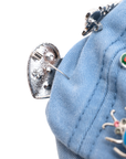 Light wash distressed denim ballcap featuring removable butterfly, ladybug, heart, and floral crystal brooch pins by Sassy Jones.