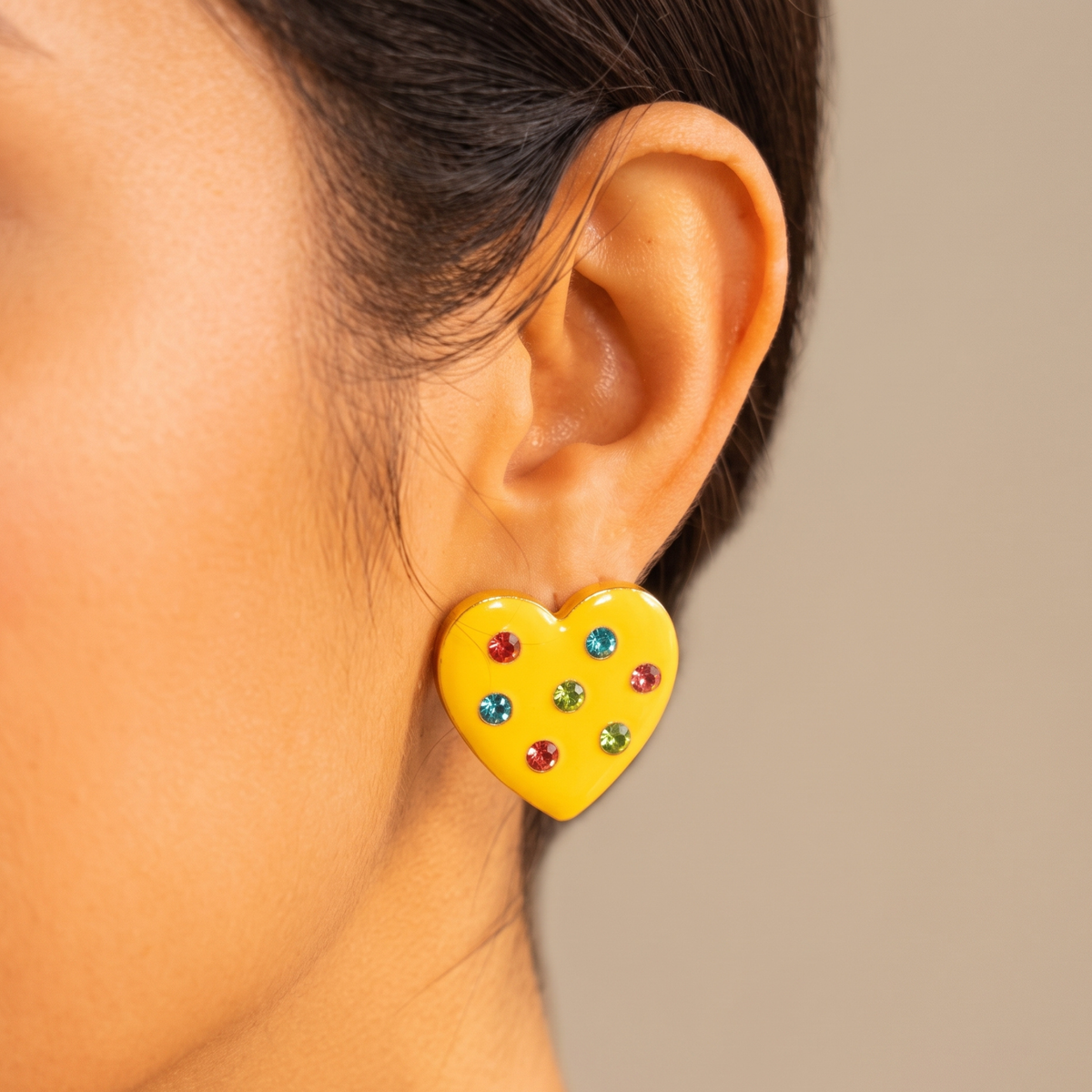 Close up of Lovebug 18K Carnivale Stud featuring seven colorful crystals across a glossy yellow heart.