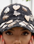 Black distressed denim ballcap featuring removable butterfly, ladybug, heart, and floral crystal brooch pins by Sassy Jones.