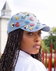 Light wash distressed denim ballcap featuring removable butterfly, ladybug, heart, and floral crystal brooch pins by Sassy Jones.