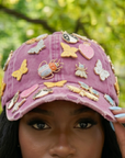 Pink distressed denim ballcap featuring removable butterfly, ladybug, heart, and floral crystal brooch pins by Sassy Jones.