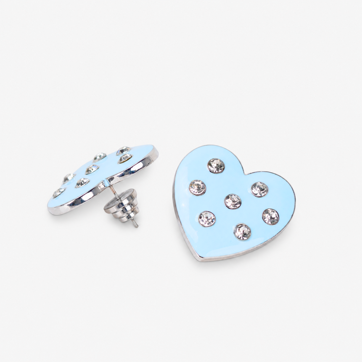 Lovebug Greige heart earring shown on model with soft blue finish and round crystal details. Oversized blue heart stud earring featuring polished edging and scattered clear crystals.
Lovebug statement studs featuring a smooth pastel blue heart silhouette with sparkling crystal accents.
Close up of Lovebug Greige Stud featuring glossy light blue finish and seven brilliant crystal details.
