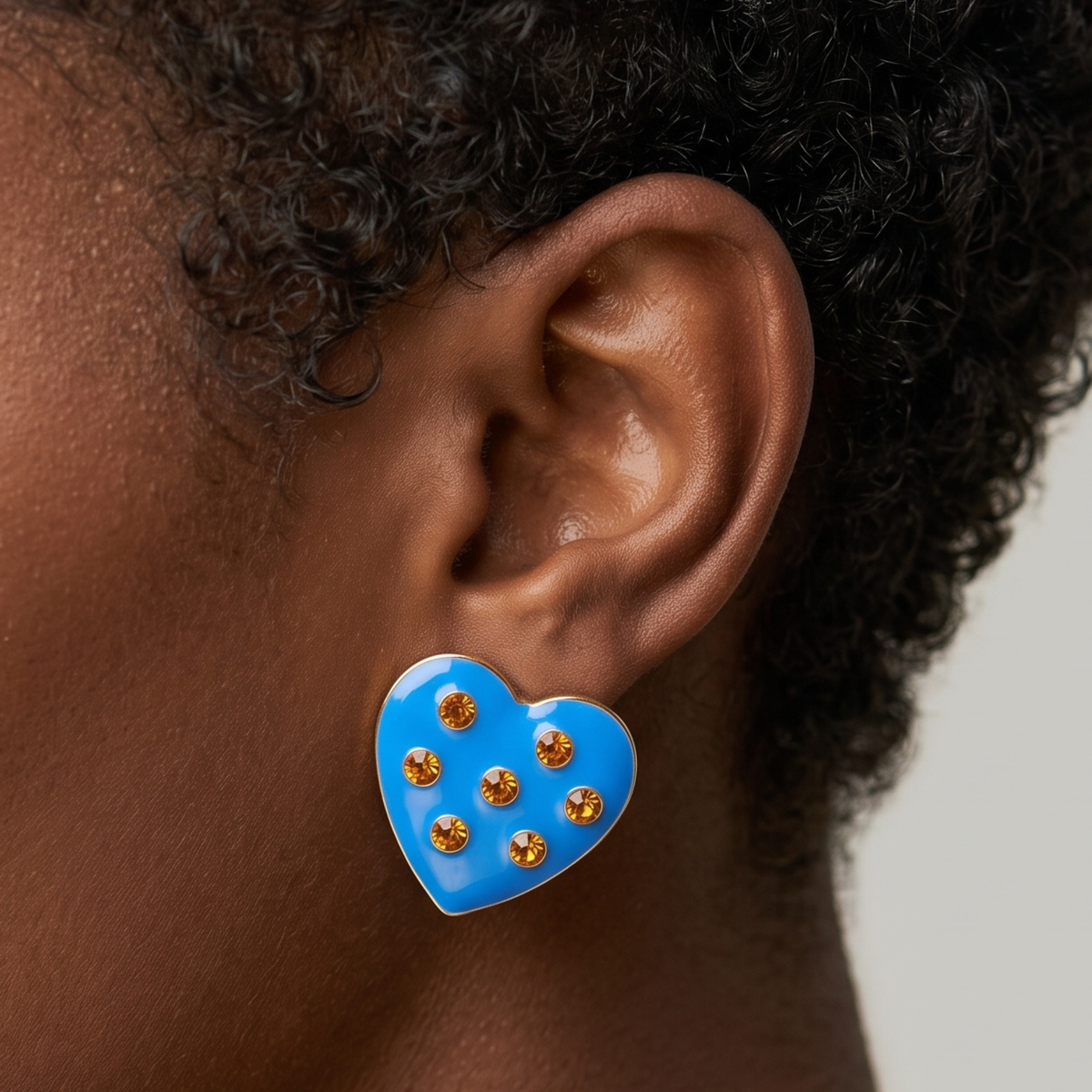 Close up of Lovebug 18K Paradise Blue Stud featuring a glossy sky blue surface and sparkling amber gold crystals.