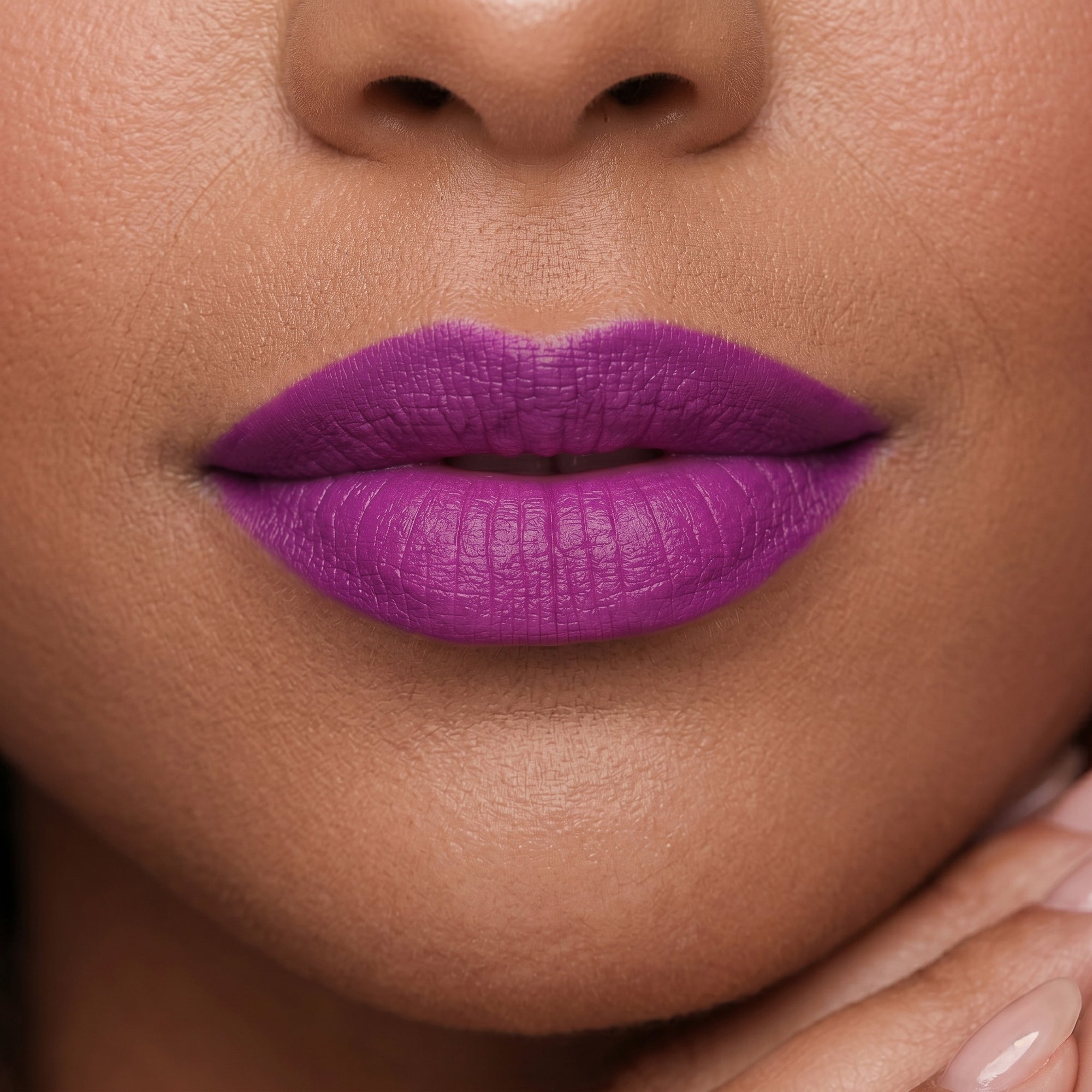 Bright purple lipstick in gold tube with vivid violet swatch for a bold, statement lip look.