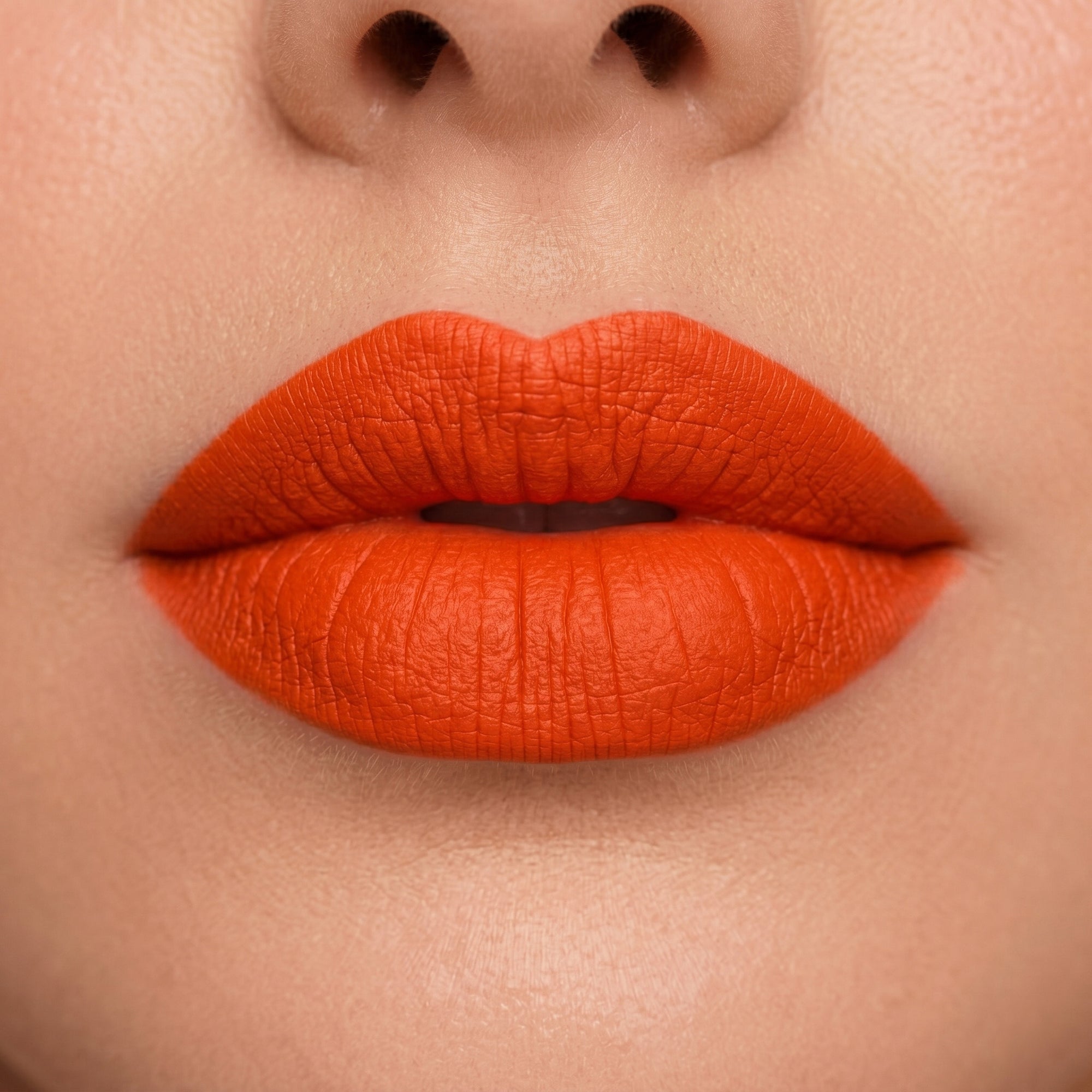 Bright coral red lipstick in gold tube with vibrant orange-red swatch for a bold statement lip.