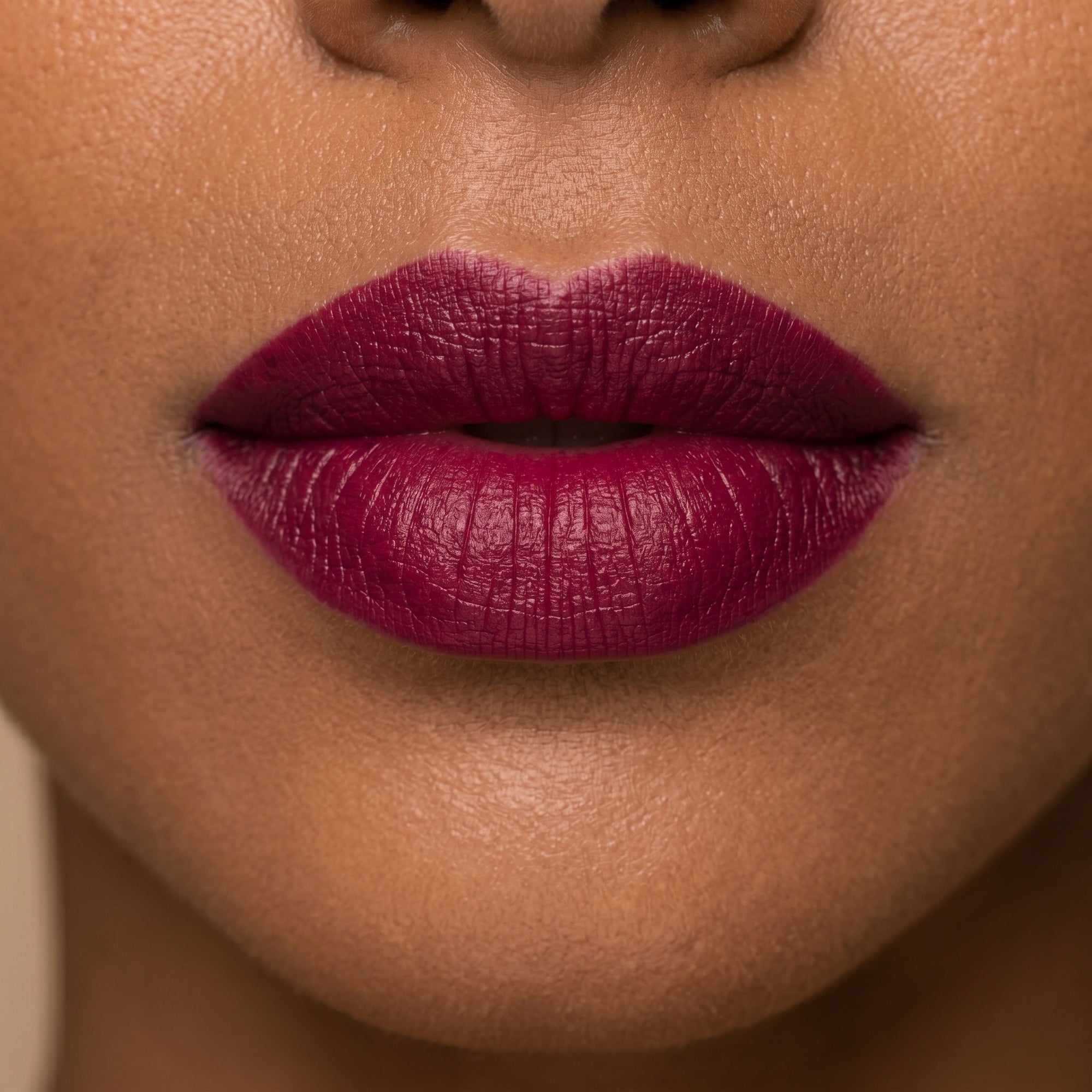 Deep berry lipstick in gold tube with rich plum swatch for a bold, luxurious lip look.