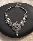 Antiqued silver statement necklace featuring sculpted fish, coral inspired branches, luminous pearl accents, shell details, and intricate ocean textures.