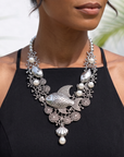 Antiqued silver statement necklace featuring sculpted fish, coral inspired branches, luminous pearl accents, shell details, and intricate ocean textures.