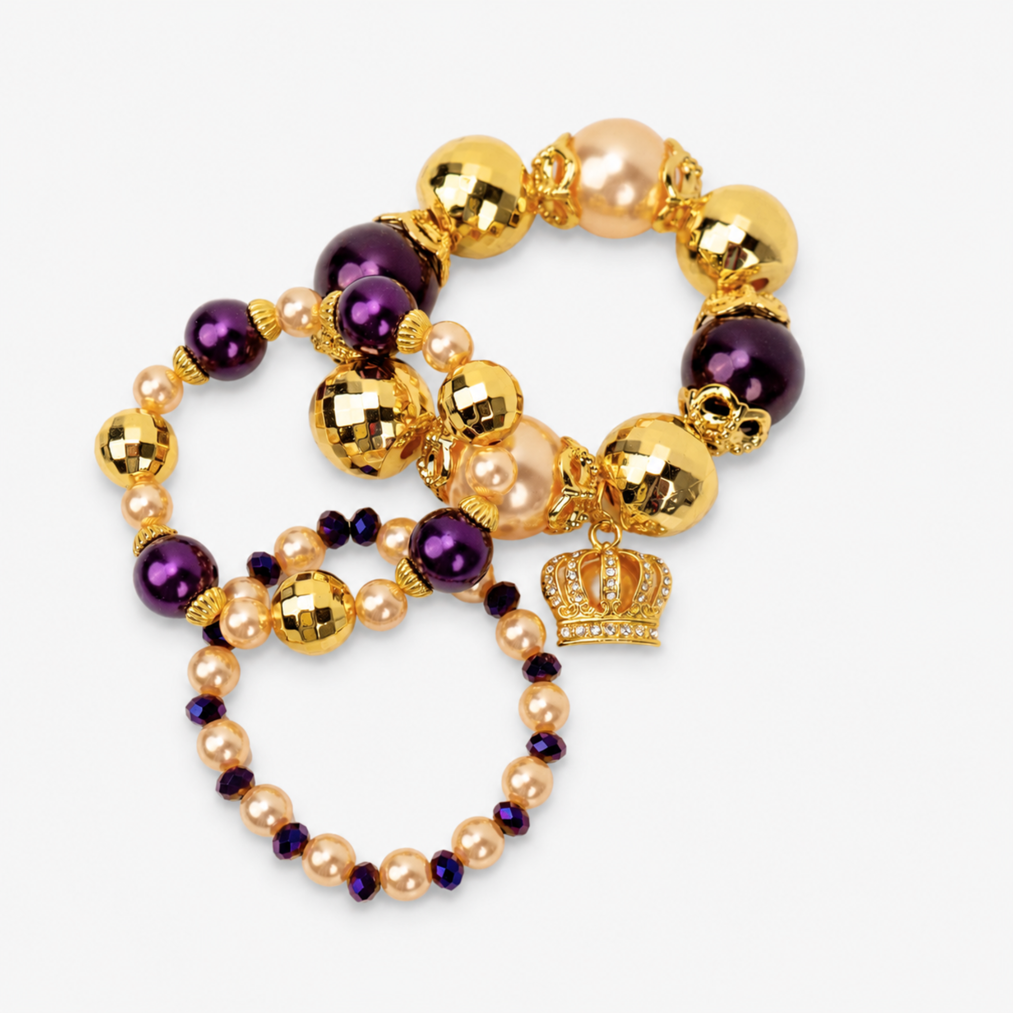 Close-up of Reign bracelet stack with oversized beads, crystal accents and jeweled gold crown charm. 