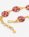 Close up of red ladybug necklace featuring black spots, petite pearl-like beads and sparkling clear crystals.