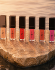 Six piece lip gloss set in pink box featuring neutral, coral, red, and pink shades with high shine finish.