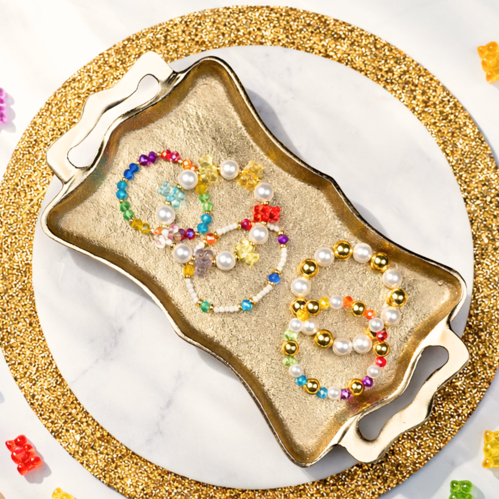 Stacked pearl and colorful bead stretch bracelets with gold accents and playful charms designed for layered wrist styling