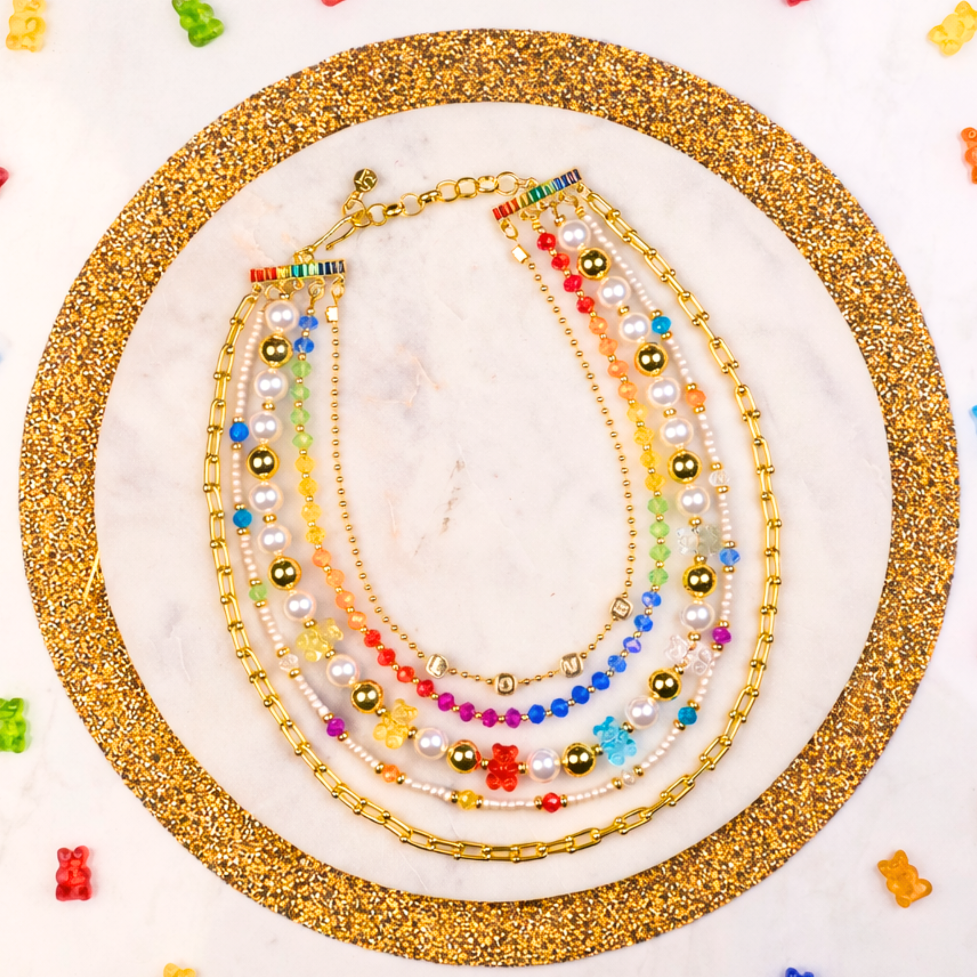 Layered 18k gold necklace with pearls, colorful beads, and playful teddy bear charms designed for fun luxury styling