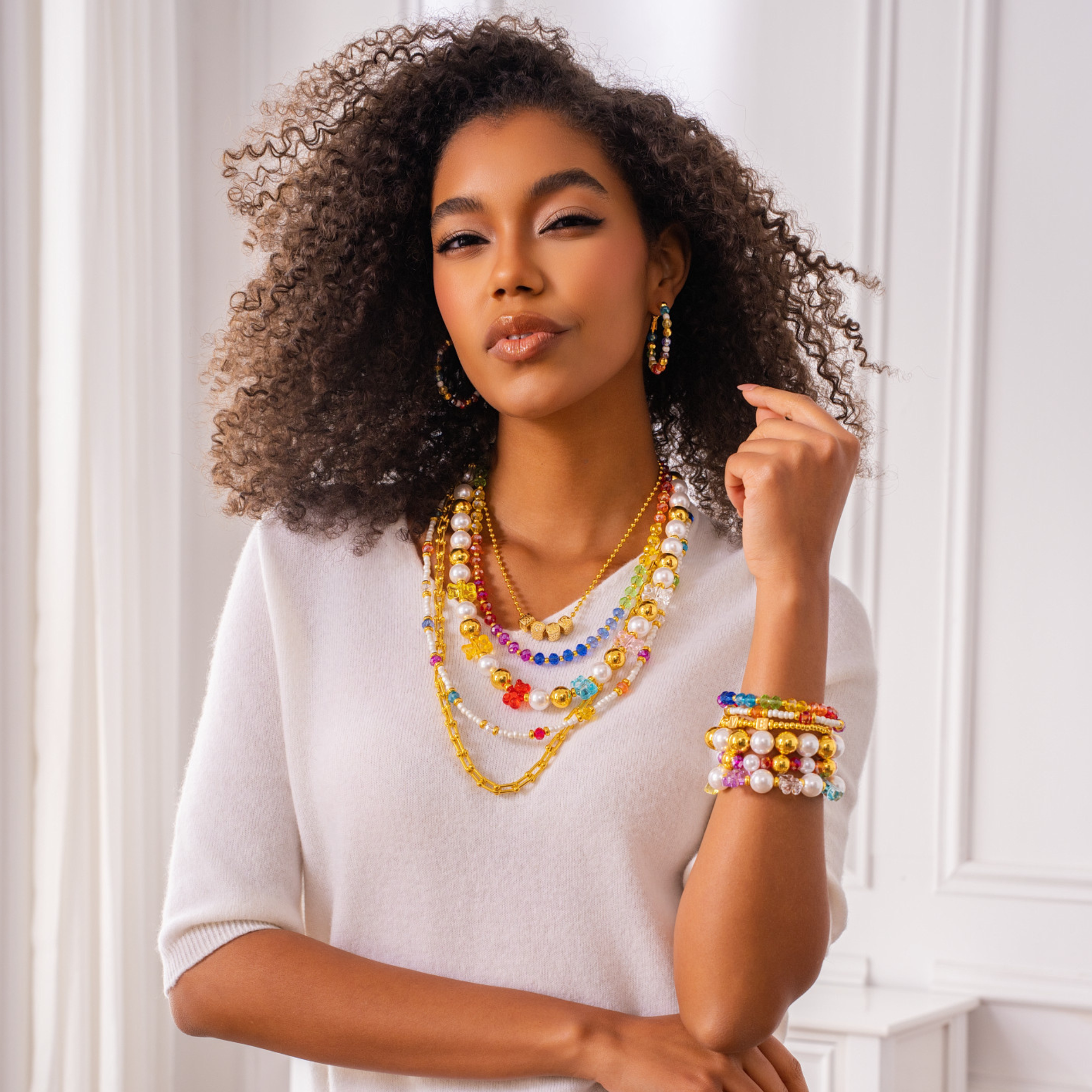 Stacked pearl and colorful bead stretch bracelets with gold accents and playful charms designed for layered wrist styling