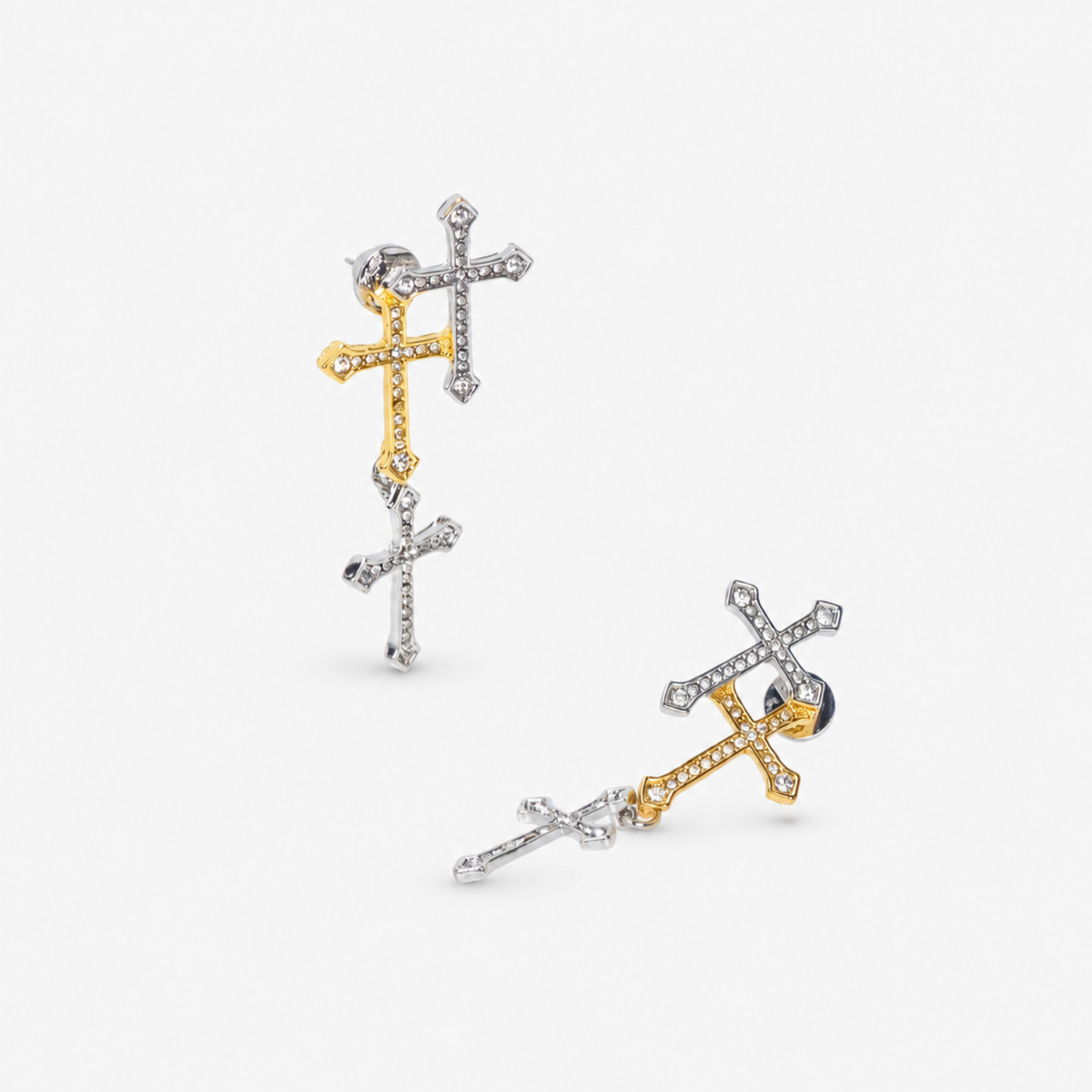 Trinity 18K Cross Sparkling Earrings featuring three cascading crystal crosses in gold and silver finishes.   Woman wearing Trinity statement earrings with layered gold and silver crystal cross motifs.   Sassy Jones Trinity drop earrings featuring three sparkling crosses in contrasting mixed metal finishes.   Close up of crystal cross earrings with a silver cross stud, gold center cross and dangling silver cross.   Trinity faith inspired earrings featuring cascading crystal embellished crosses in gold and s