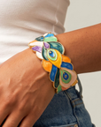 Sculptural peacock inspired cuff bracelet with colorful hand painted enamel style detailing and Gold tone finish.