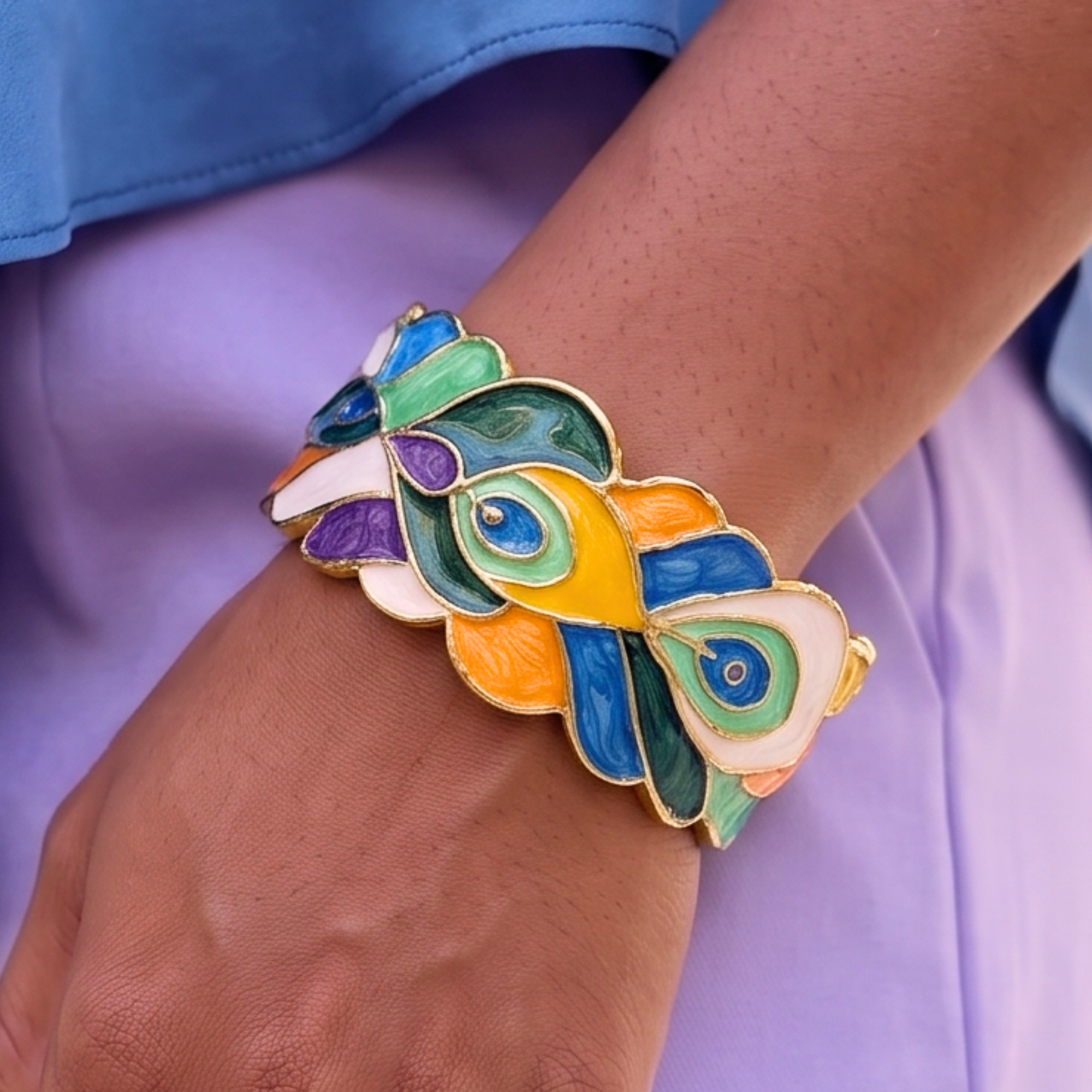 Statement cuff bracelet featuring hand painted enamel peacock feather motifs in vibrant jewel tones with gold tone detailing.