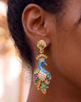 Statement peacock earrings featuring hand painted enamel feathers, sparkling crystal accents, gold shell studs, and colorful jewel toned detailing.