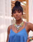 Statement peacock necklace featuring hand painted enamel feathers, multicolored crystal accents, gold tone detailing, and a sculptural peacock centerpiece.
