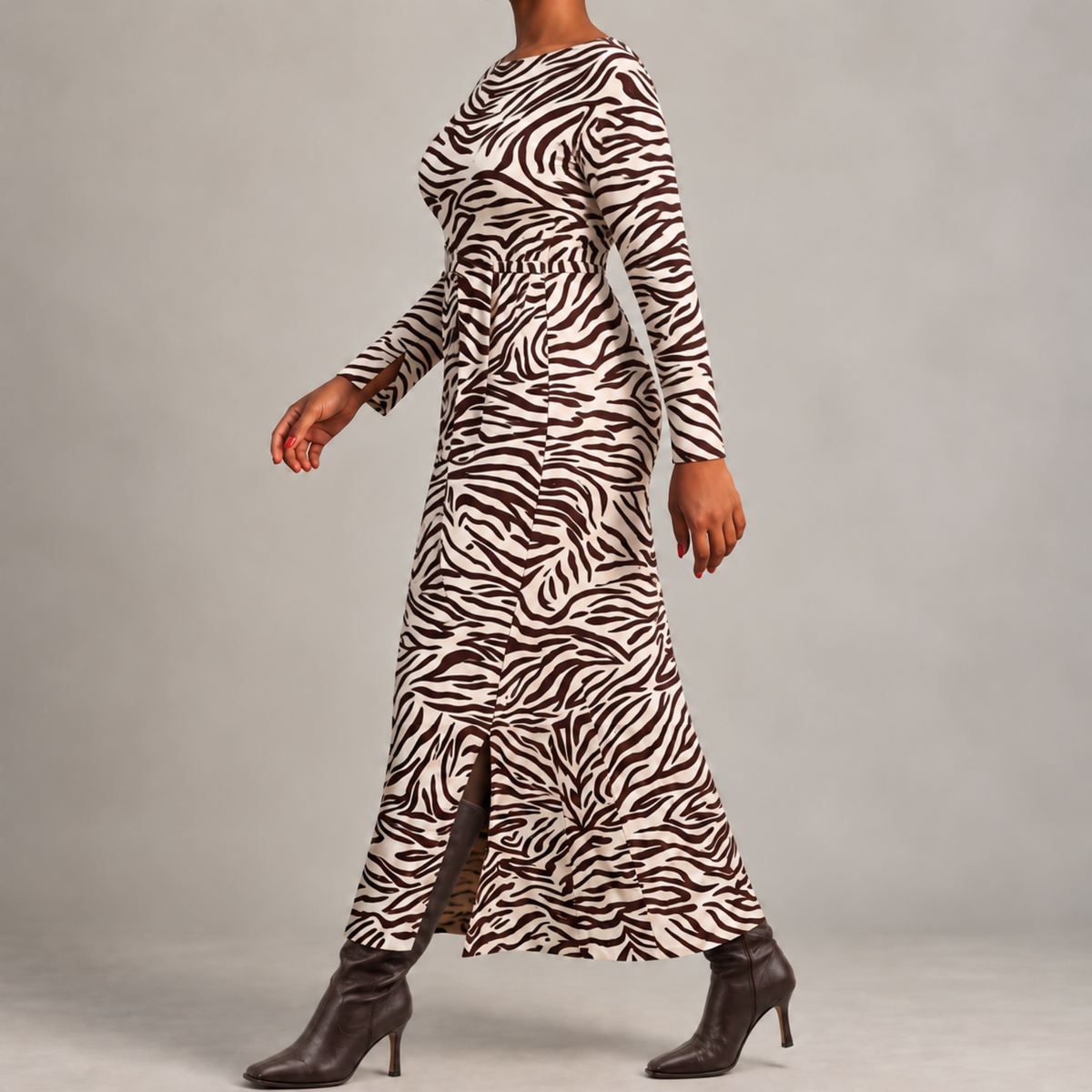 A woman modeling a long-sleeve maxi dress with a brown and white zebra print, paired with dark brown heeled ankle boots, against a neutral gray studio background.
